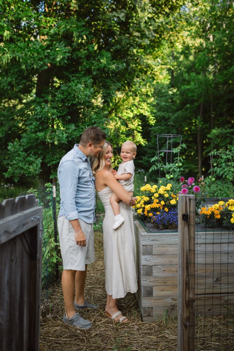 a man and woman holding a baby in a garden