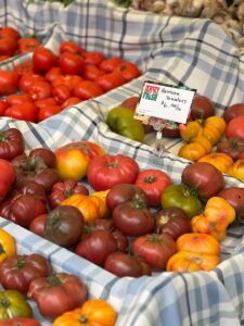 Colorful heirloom tomatoes displayed on a market stall with price tag.