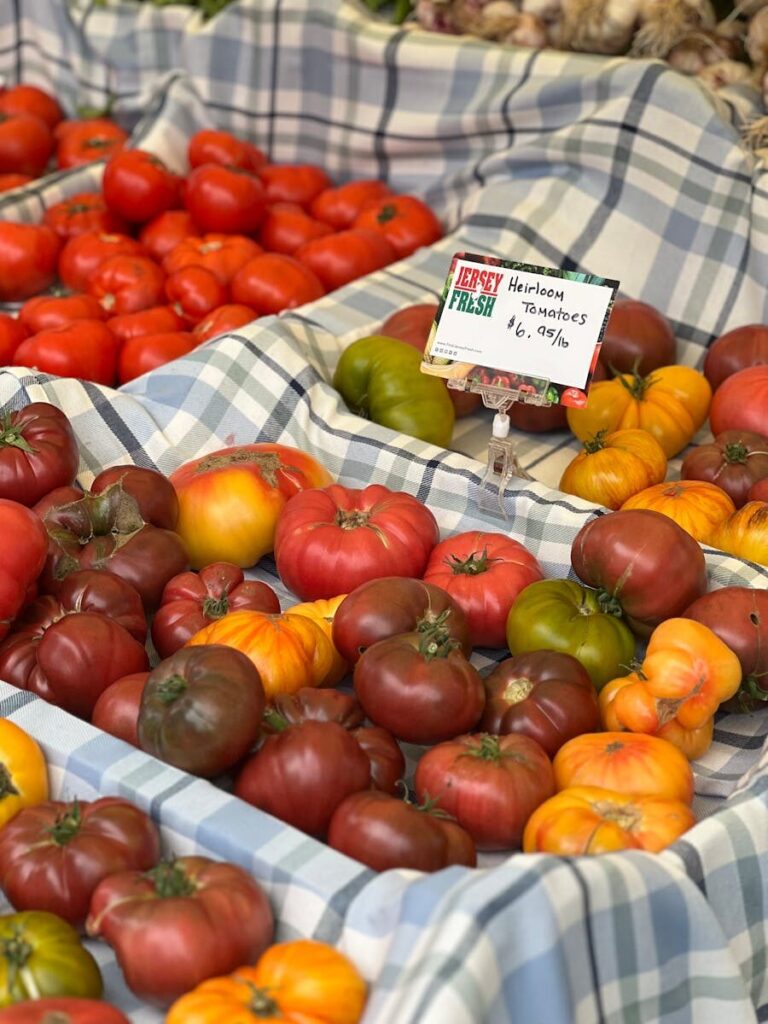 Colorful heirloom tomatoes displayed on a market stall with price tag.